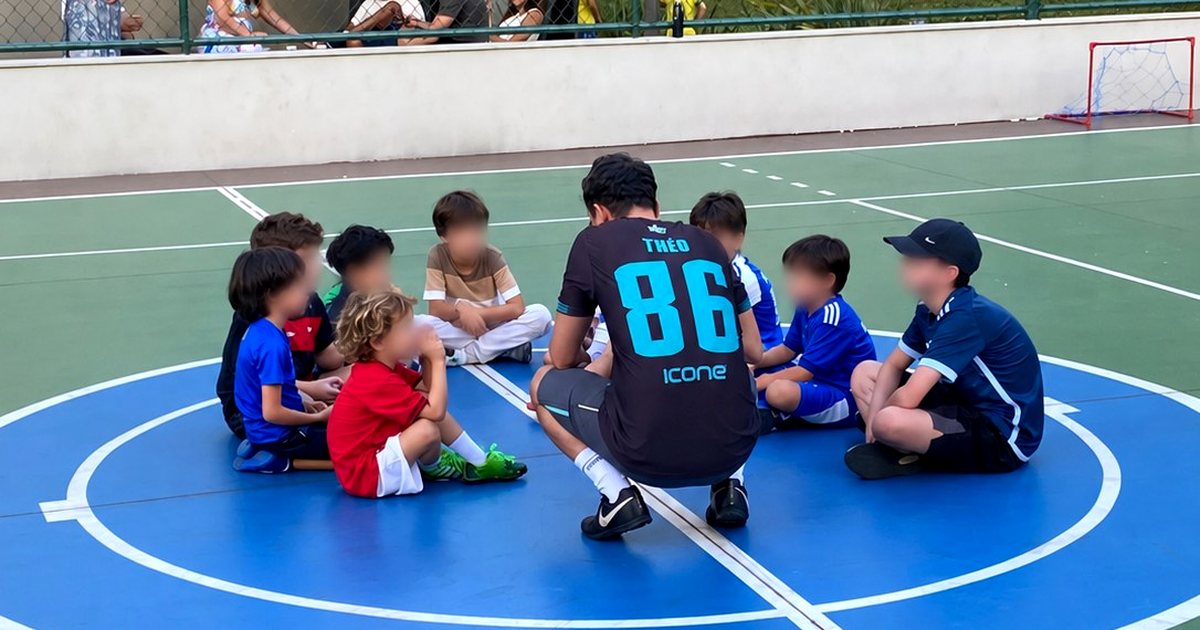 Crianças reunidas em círculo com a equipe de recreação esportiva em uma quadra
